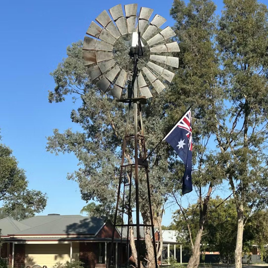 Australian flag flying beside a traditional windmill in a rural Australian setting