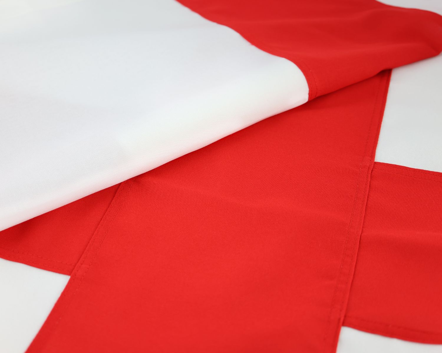 Folded detail photo of the fully sewn England flag showing the red St George cross and white fabric.