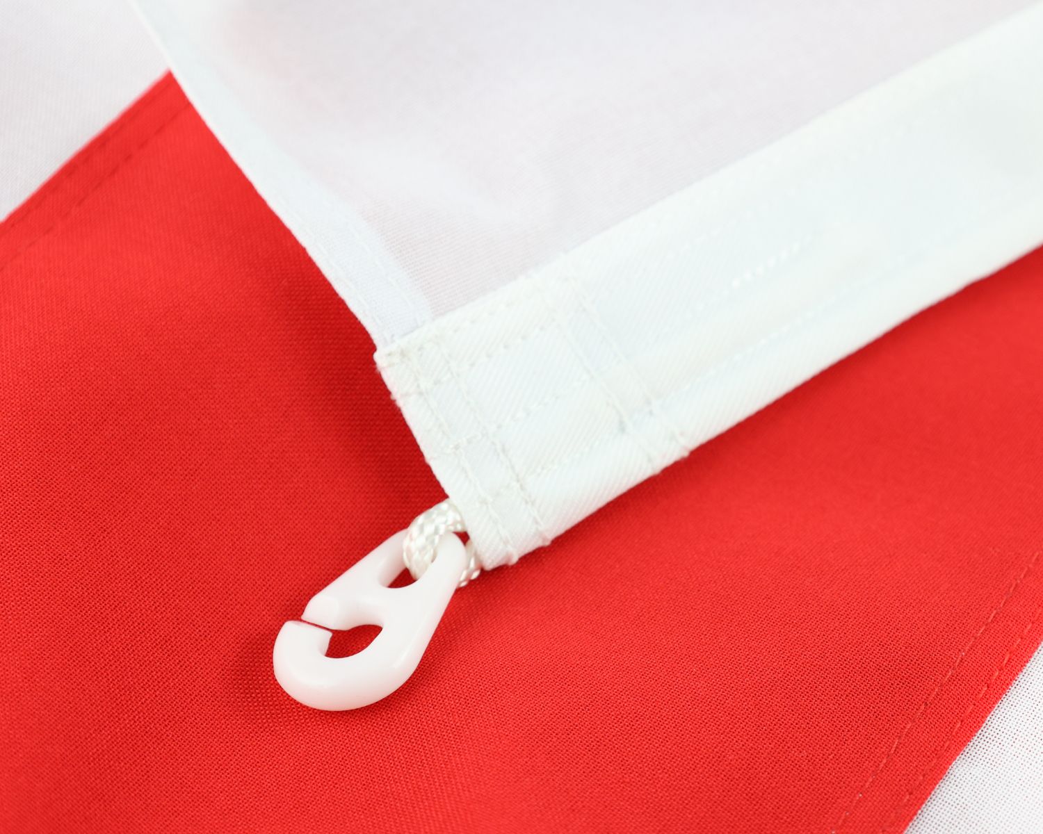 Close-up of the fully sewn England flag showing the white header and plastic toggle attachment.